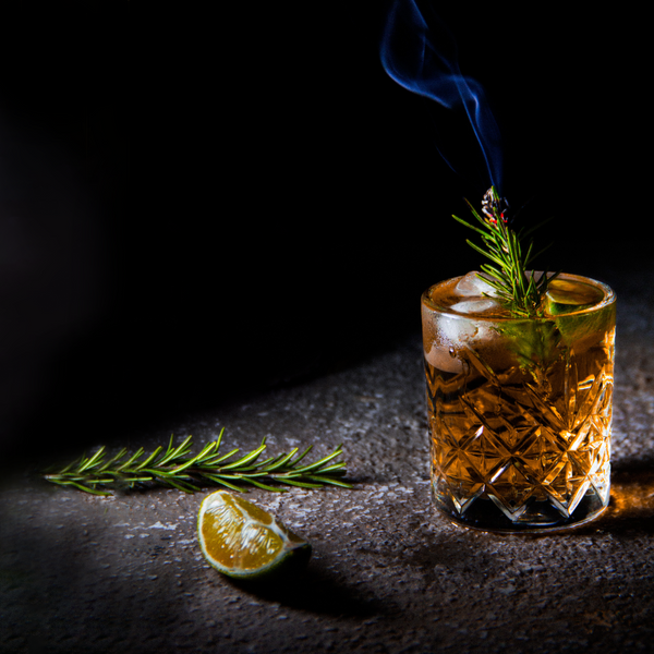 Cocktail glass with a sprig of rosemary smoking