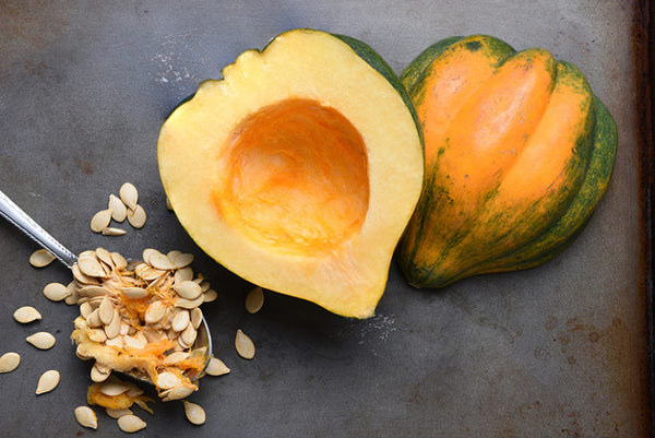 Photo of a baked squash with seeds removed on a dark surface. The first step of this recipe before it is baked.