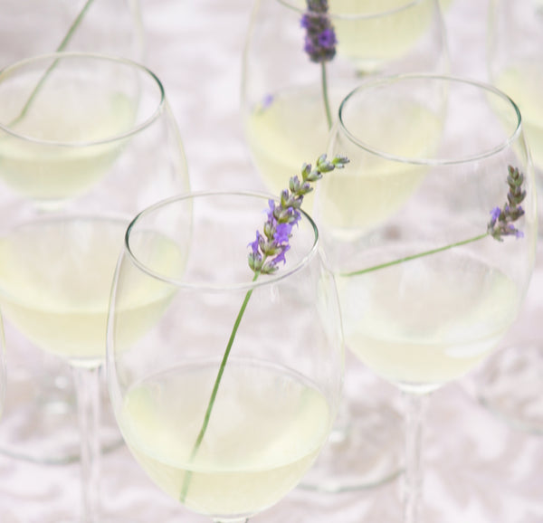 Lavender Royale Cocktail in wine glass topped with lavender sprig