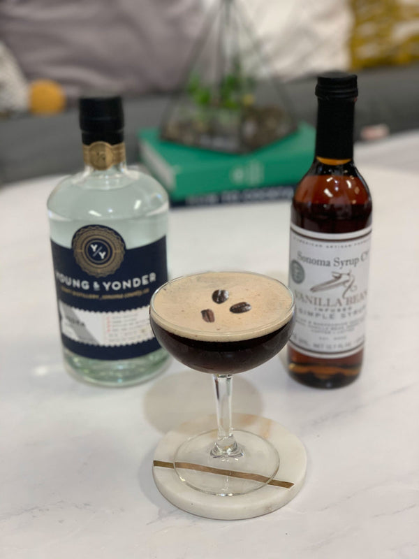 Picture of espresso martini cocktail next to Sonoma Syrup Co's Vanilla Bean Simple Syrup and Young & Yonder's Vodka