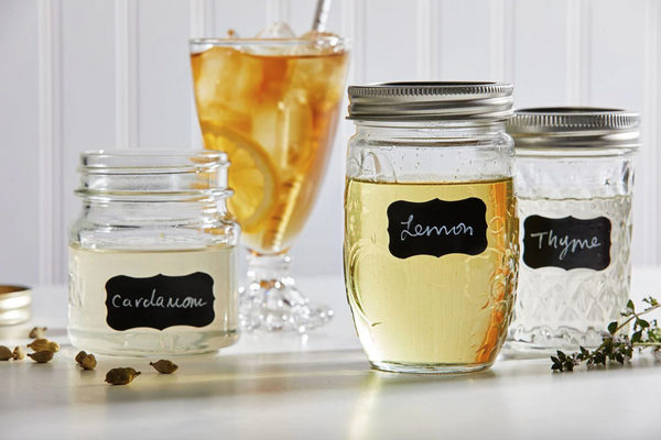 Photo of three mason jars filled with simple syrups and one glass of iced tea.