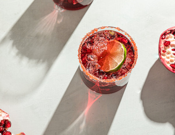 Picture of two deep red margaritas in cocktail glasses topped with a fresh lime and salt rim